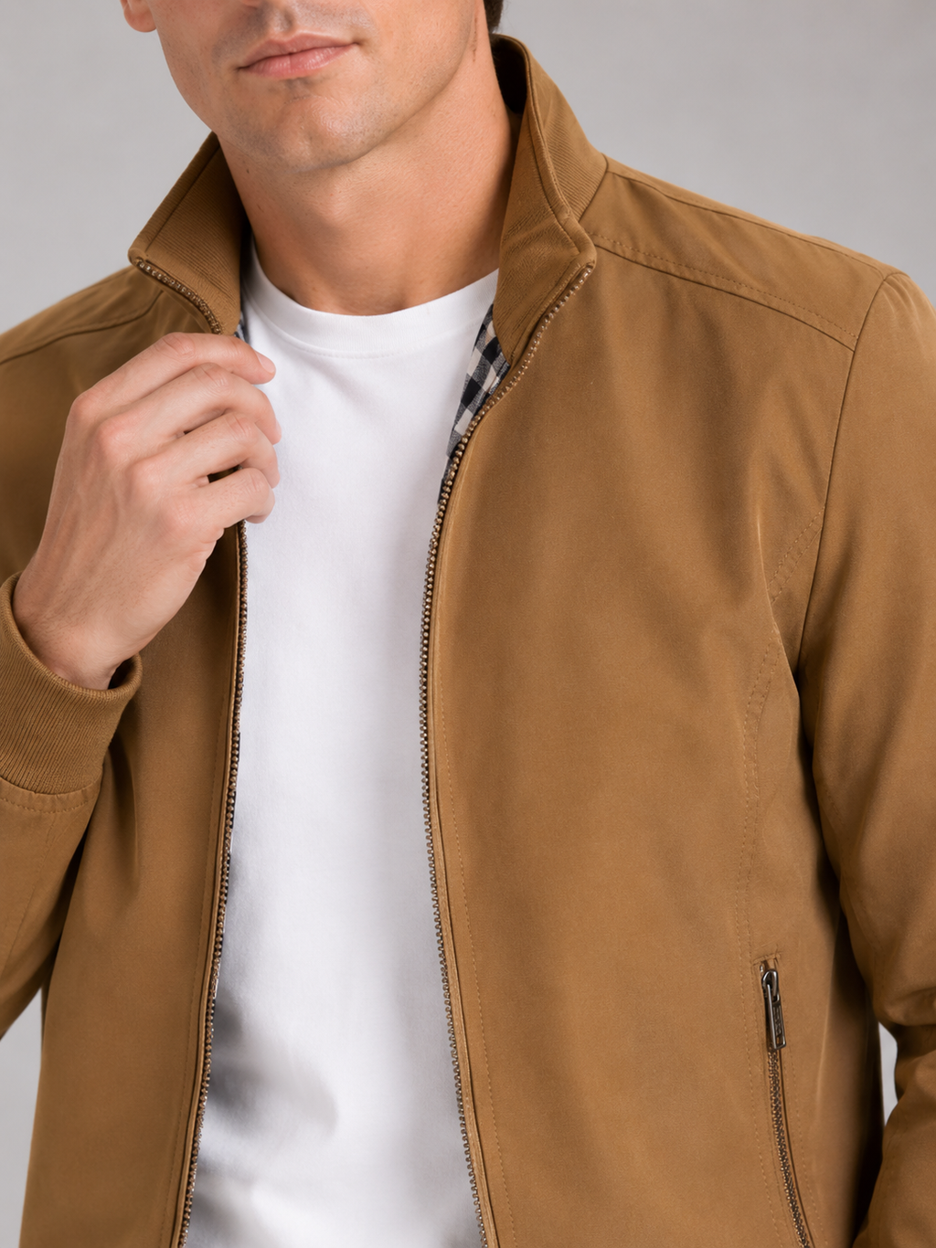 Close up of khaki bomber jacket showing smooth fabric and refined zipper collar detail