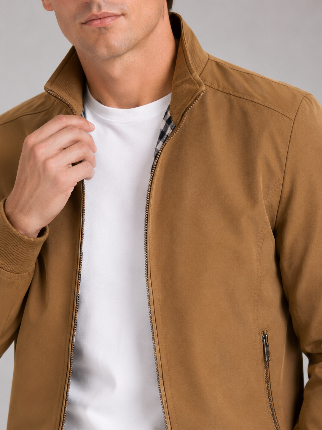 Close up of khaki bomber jacket showing smooth fabric and refined zipper collar detail