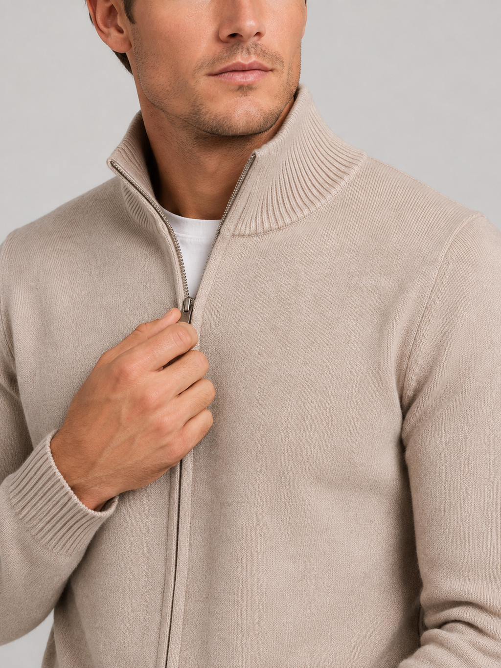 Close-up of a khaki full zip knit sweater showing the textured knit fabric, stand collar, zipper closure, ribbed cuffs, hem, and stitching details