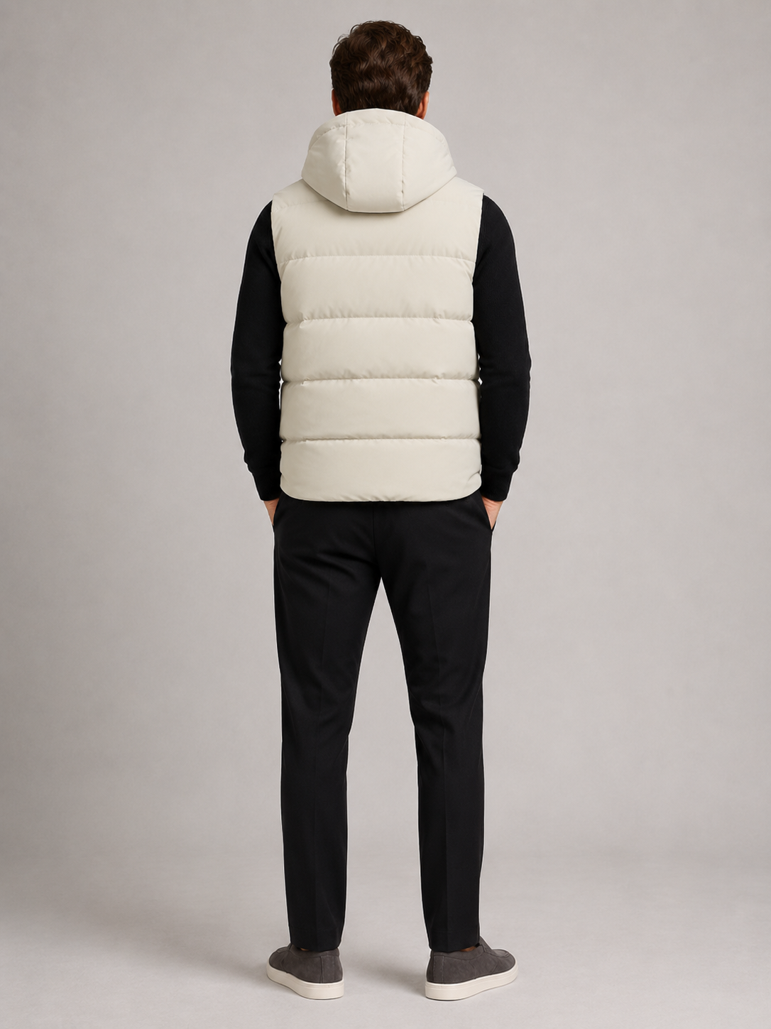 Back view of a man wearing a beige hooded puffer vest showing the attached hood, padded construction, sleeveless cut, and comfortable fit