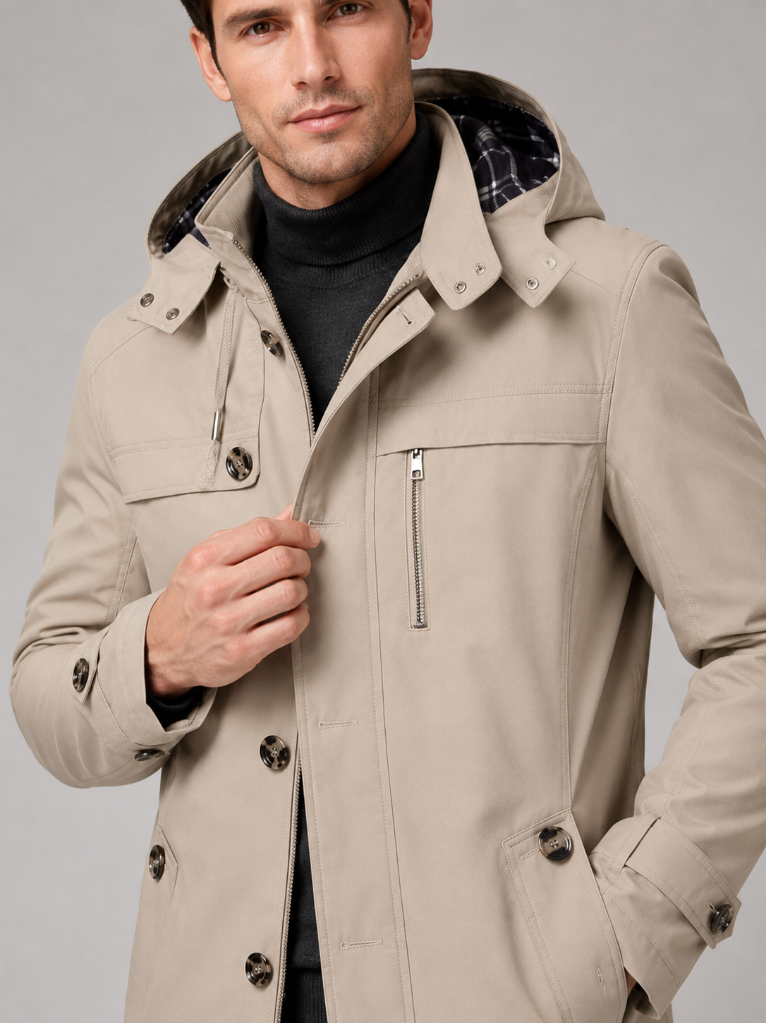 Close up of beige hooded trench coat showing thick cotton fabric, attached hood, and button front detail