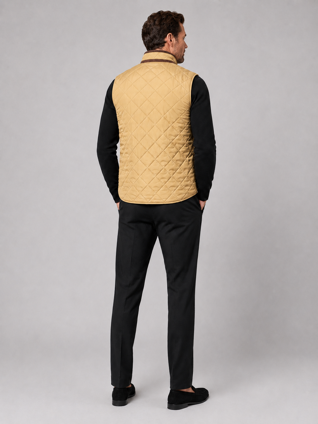 Back view of a man wearing a khaki quilted vest showing the padded construction, sleeveless cut, and comfortable fit