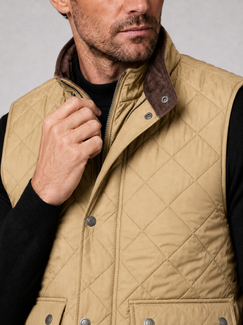 Close-up of a khaki quilted vest showing the stitched pattern, polo collar, thick padding, front closure, utility pockets, armholes, and reinforced seams