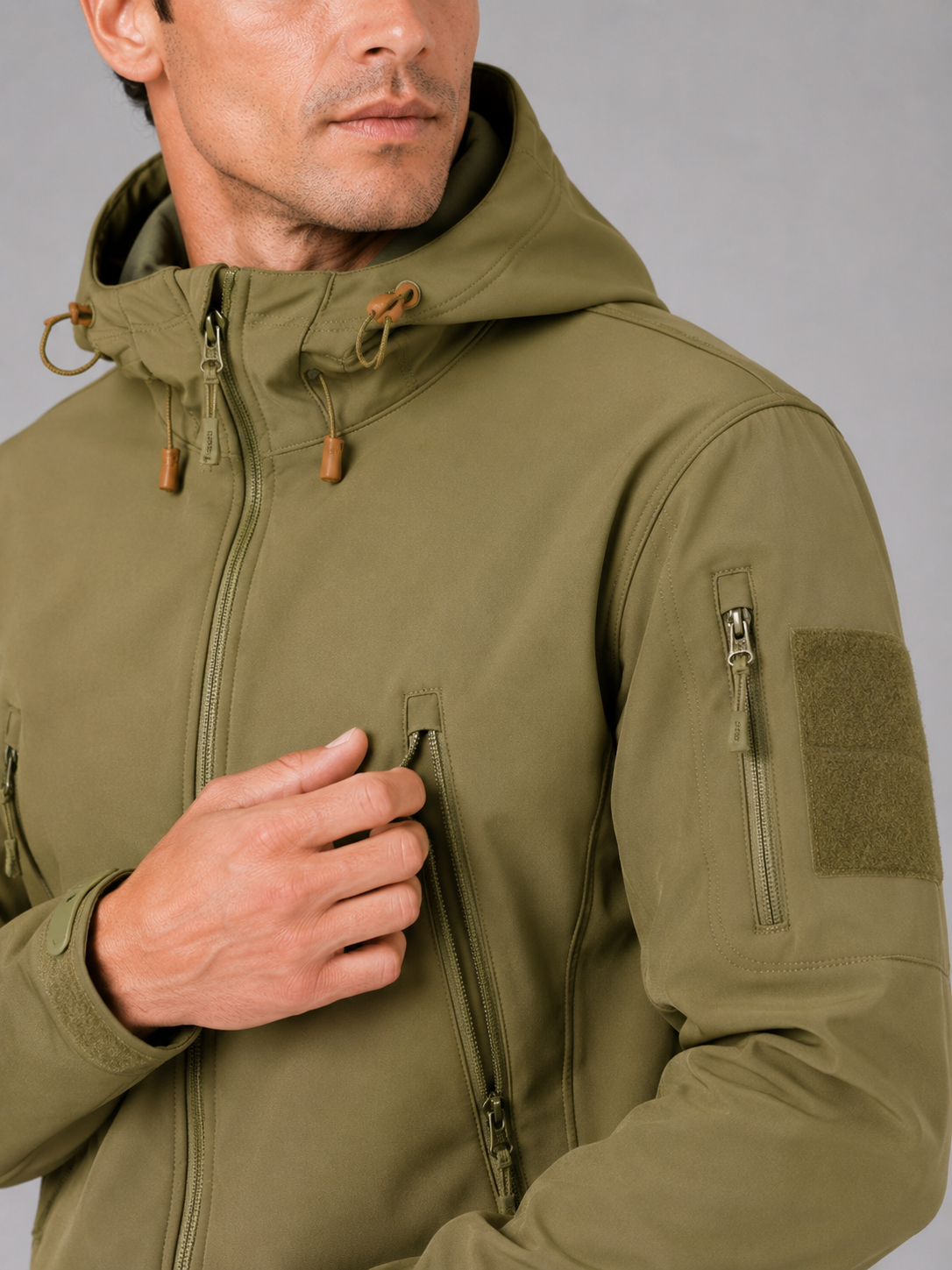 Close up of khaki tactical jacket showing waterproof soft shell fabric and hood detail