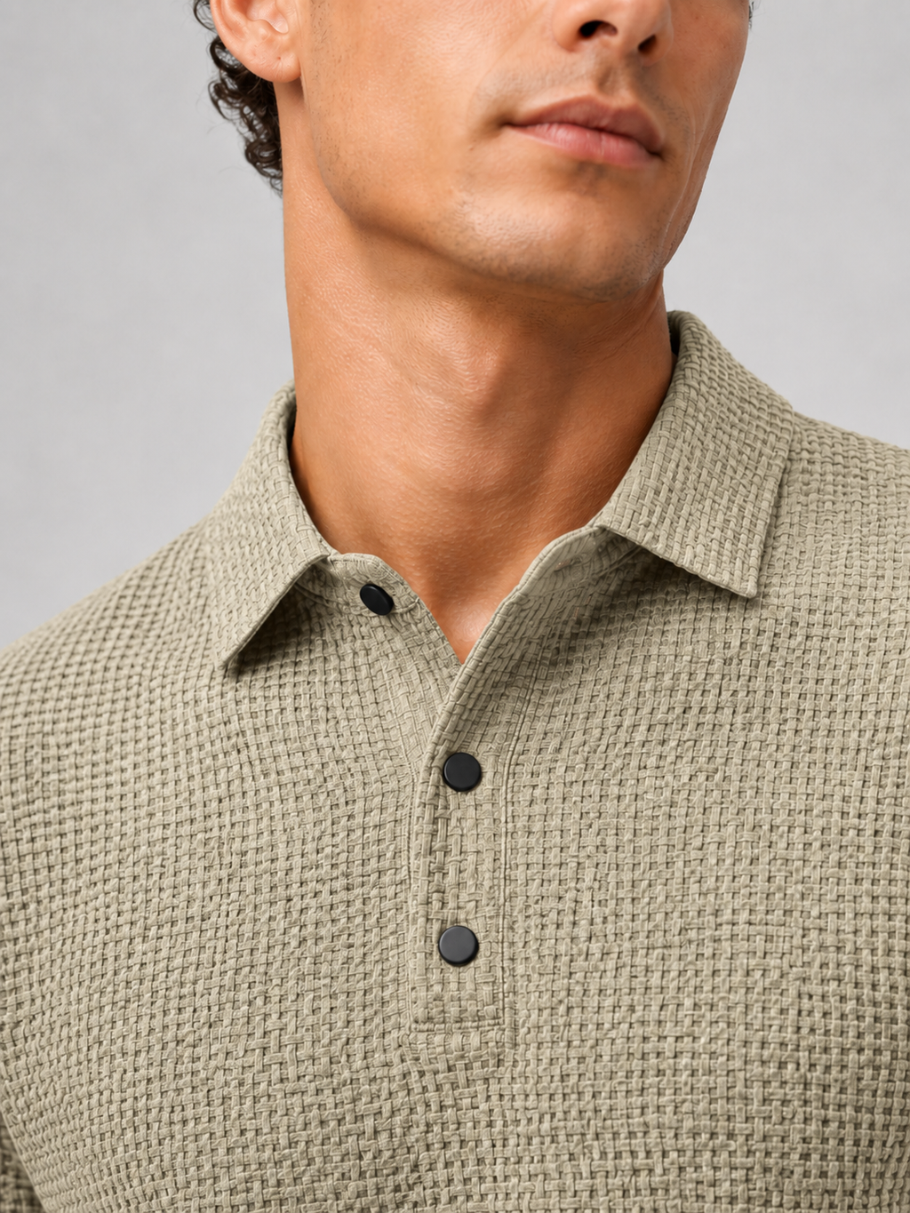 Close up of khaki textured knit polo fabric showing breathable weave and button placket detail