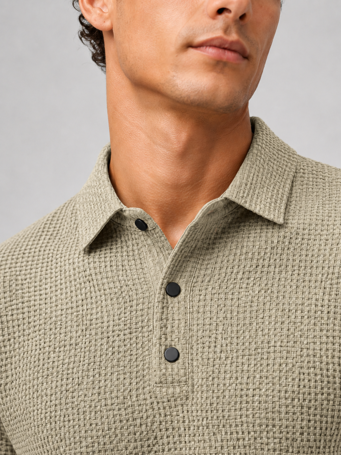 Close up of khaki textured knit polo fabric showing breathable weave and button placket detail