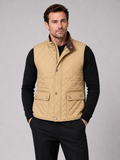 Front view of a man wearing a khaki quilted vest with a polo collar, padded construction, and multiple utility pockets