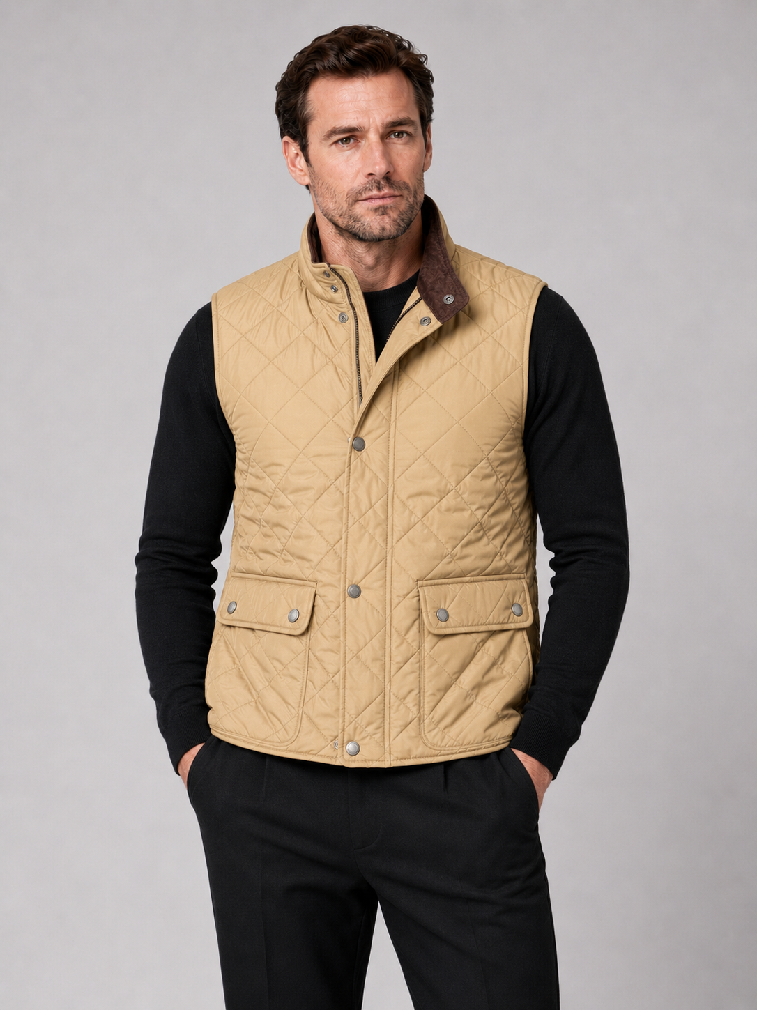 Front view of a man wearing a khaki quilted vest with a polo collar, padded construction, and multiple utility pockets