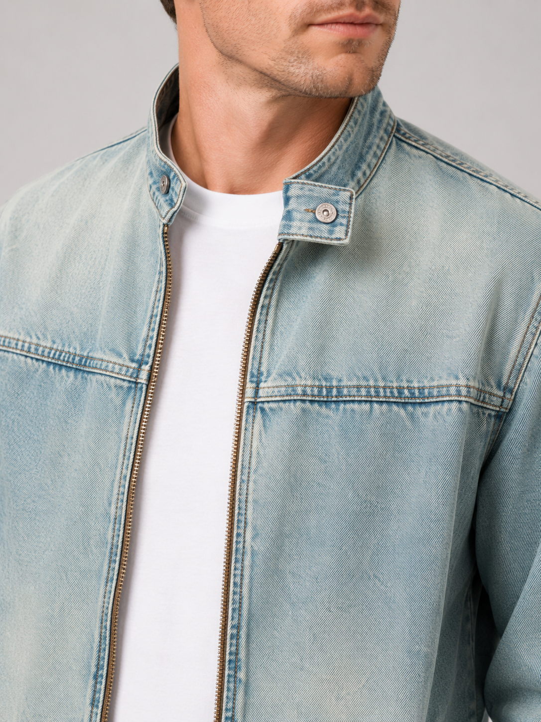Close up of light blue denim jacket showing washed cotton texture and durable zipper detail