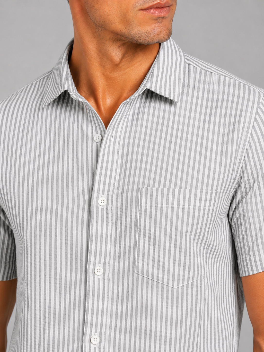 Close up of light gray seersucker shirt showing textured striped fabric and button up detail