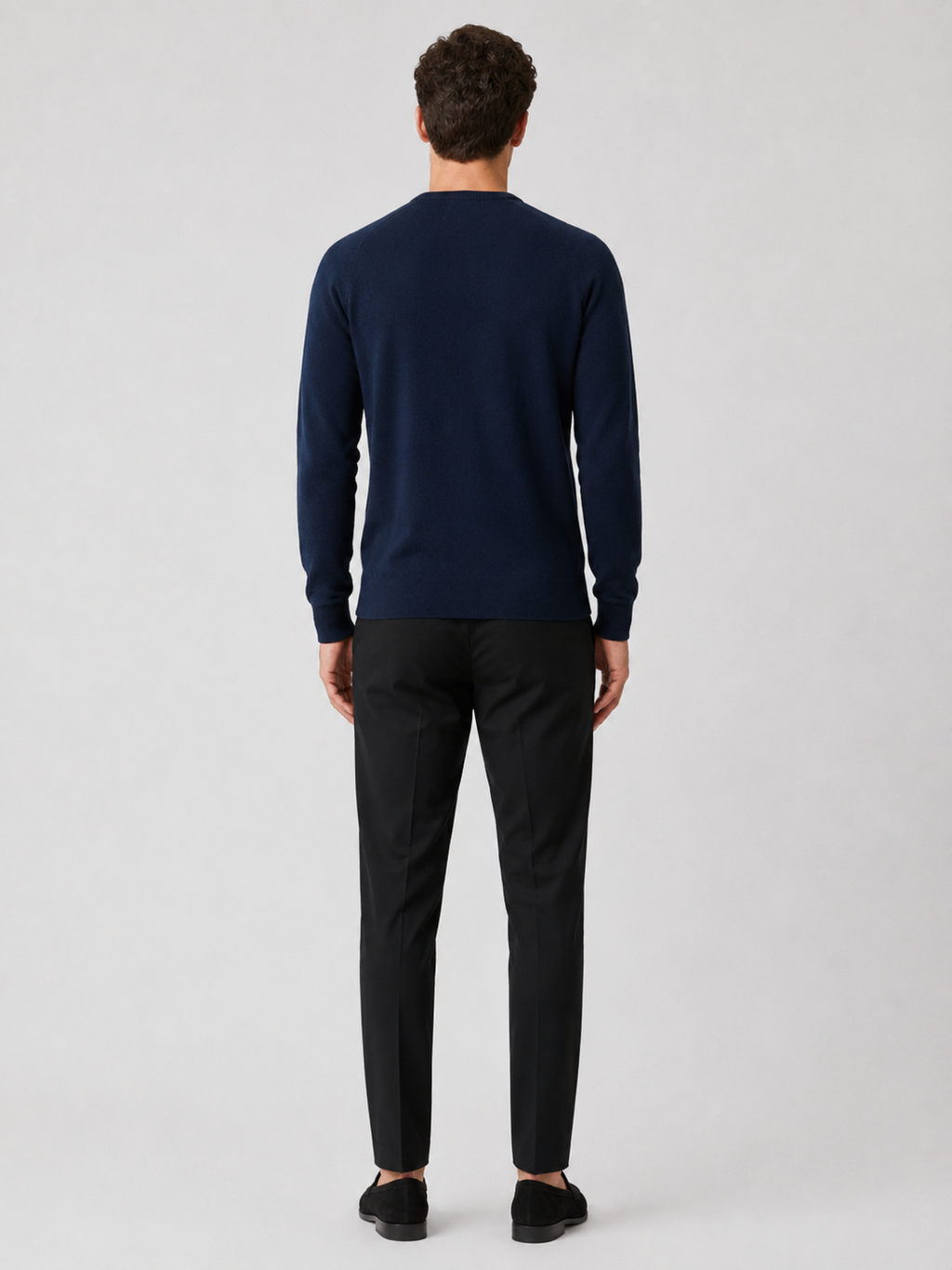 Back view of a man wearing a navy argyle sweater showing the crew neck, long sleeves, and comfortable fit