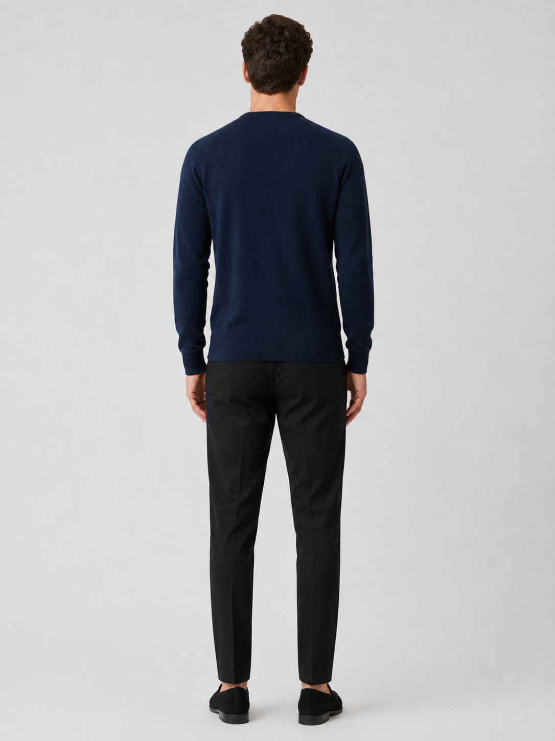 Back view of a man wearing a navy argyle sweater showing the crew neck, long sleeves, and comfortable fit