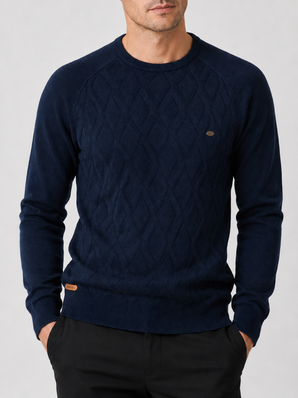 Close-up of a navy argyle sweater showing the diamond knit pattern, crew neckline, ribbed cuffs, hem, and warm texture