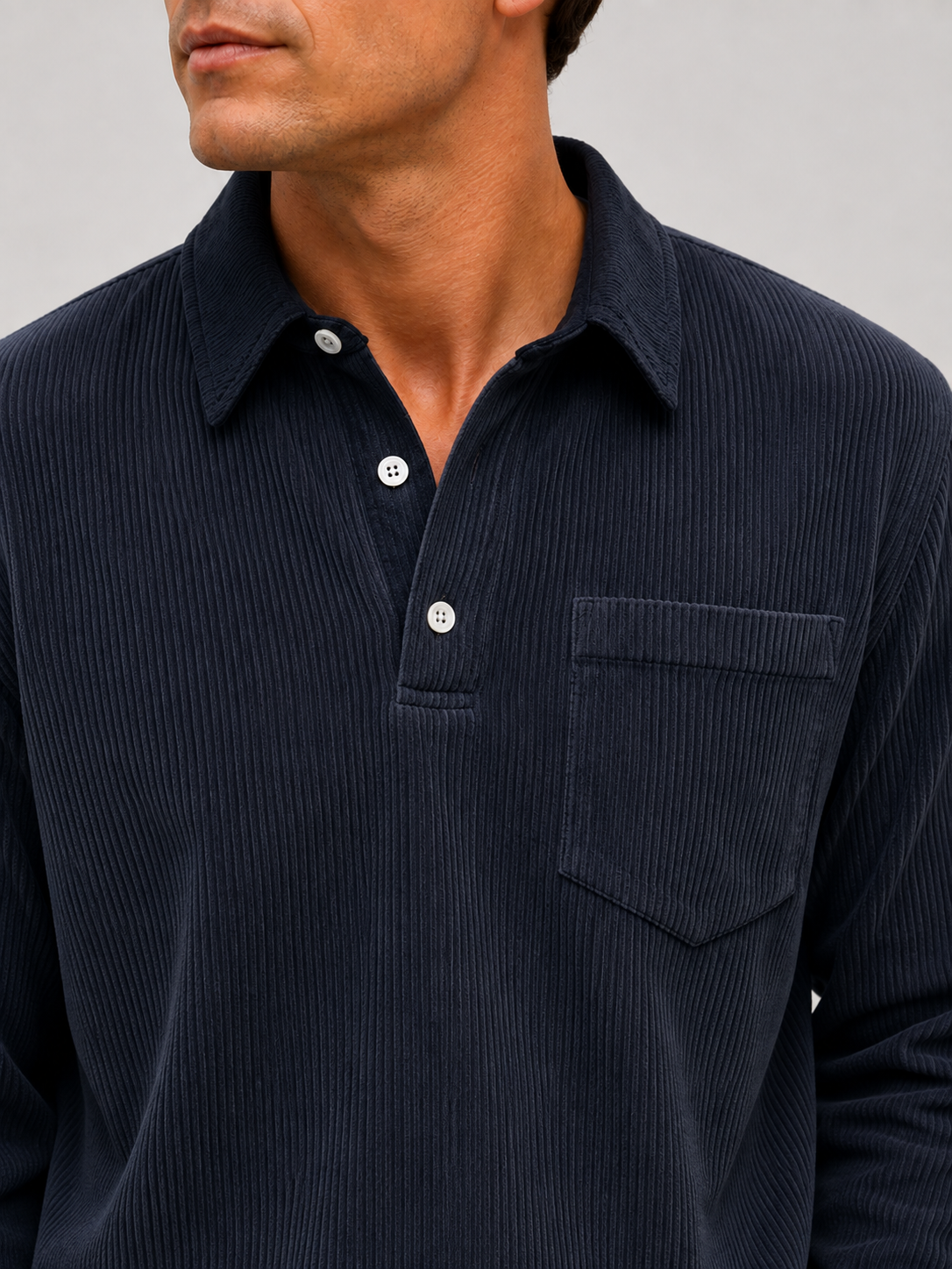 Back view of a man wearing a navy corduroy polo shirt showing the long sleeves, relaxed fit, and soft textured fabric
