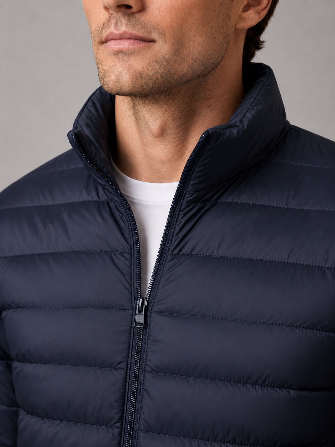 Close up of navy down puffer jacket showing insulated quilting, stand collar, and weather resistant fabric detail
