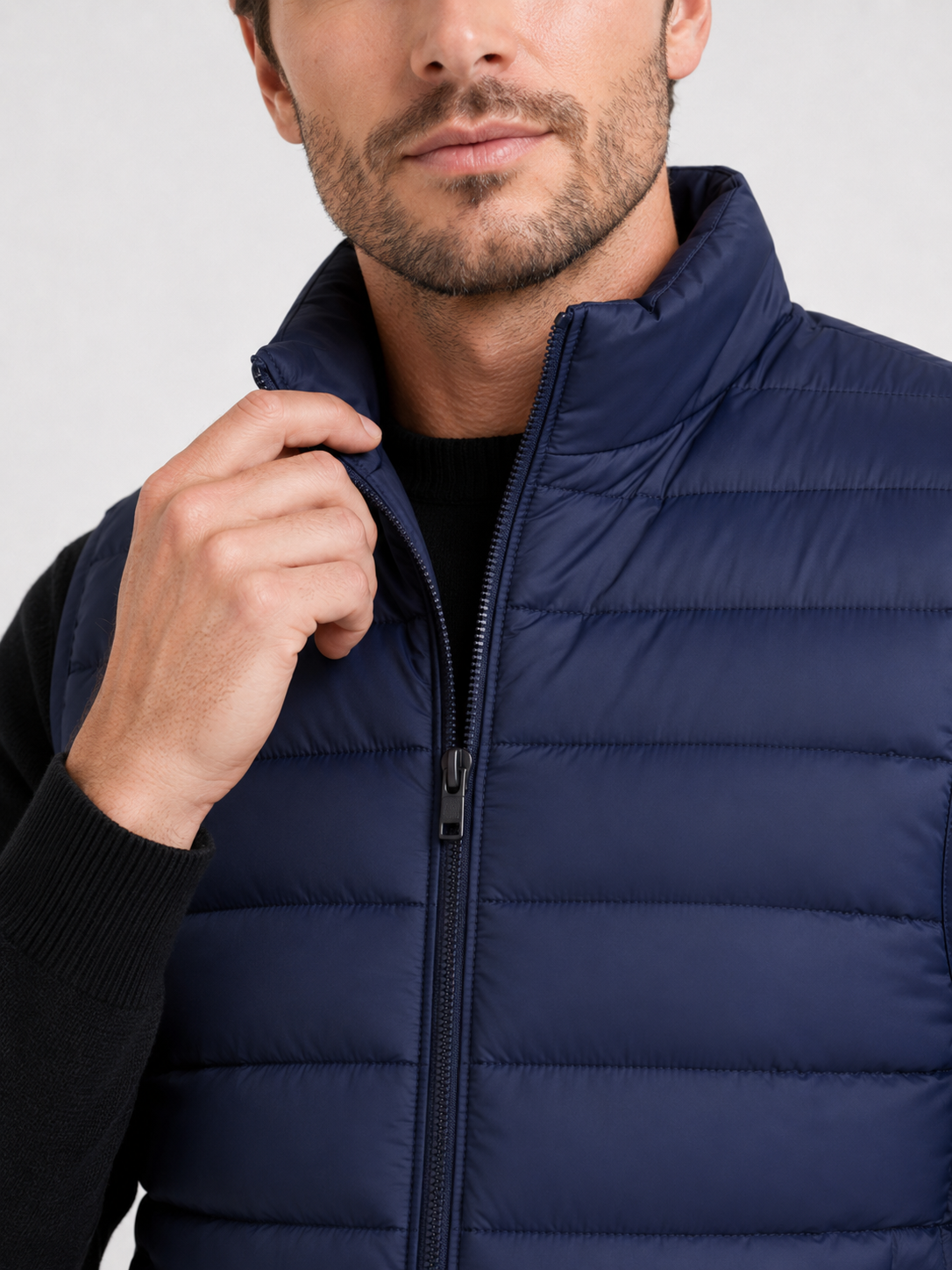 Close up of navy down puffer vest showing thick quilted insulation, zip up front, and weather resistant fabric detail