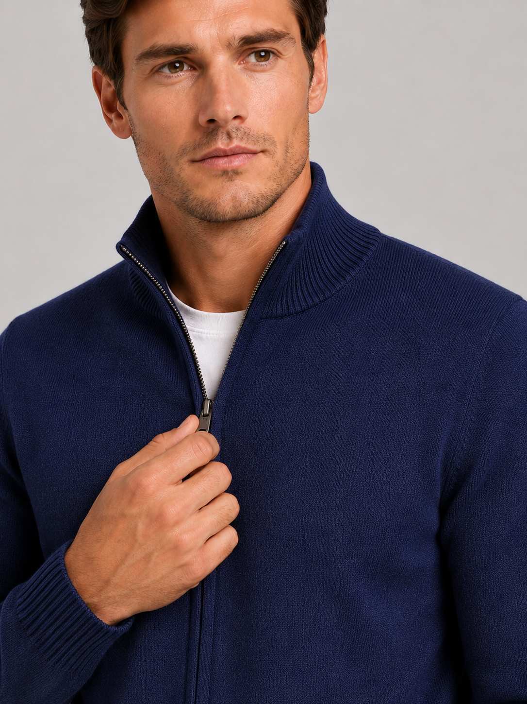 Close-up of a navy full zip knit sweater showing the textured knit fabric, stand collar, zipper closure, ribbed cuffs, hem, and stitching details