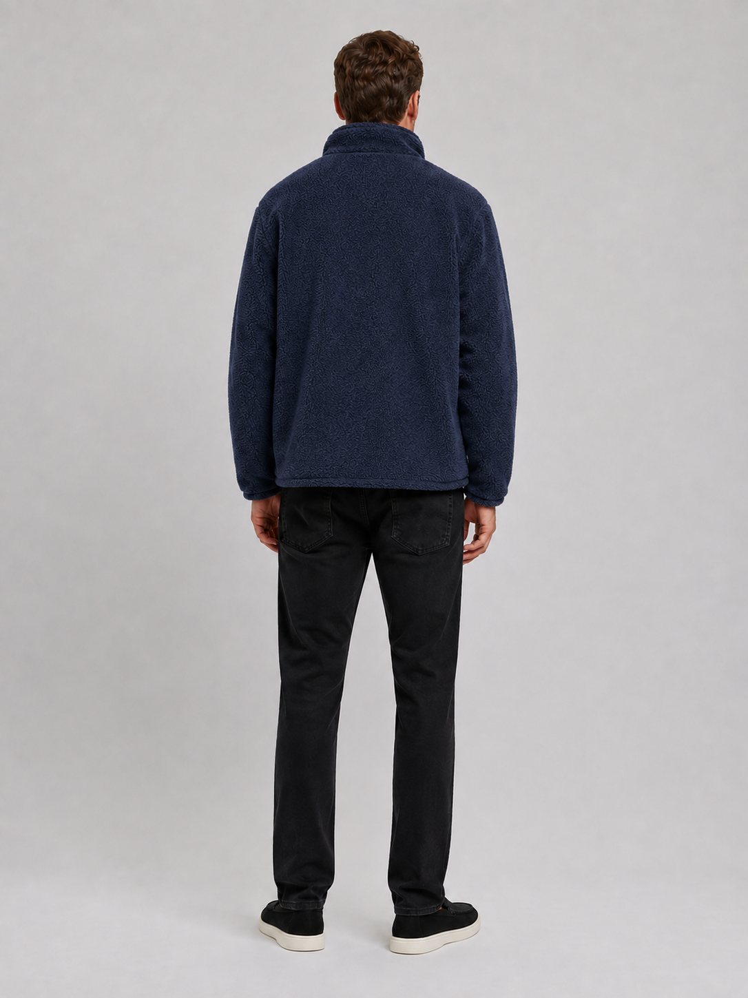 Back view of a man wearing a navy fleece jacket showing the relaxed loose fit, long sleeves, stand collar, and soft fleece construction