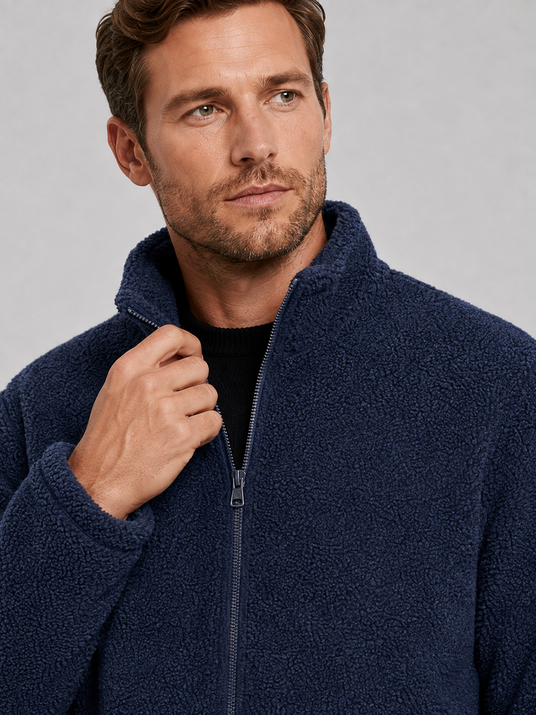 Close-up of a navy fleece jacket showing the soft fleece texture, full zipper, stand collar, pockets, cuffs, hem, and stitching details