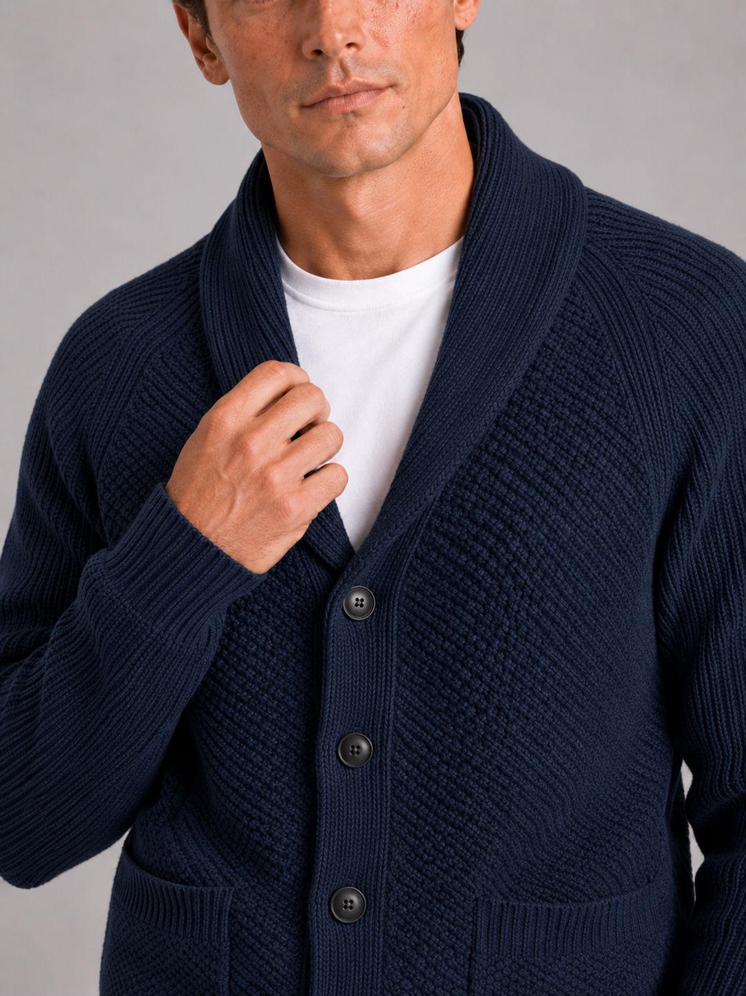 Close up of navy knit cardigan showing soft textured fabric and front pocket detail