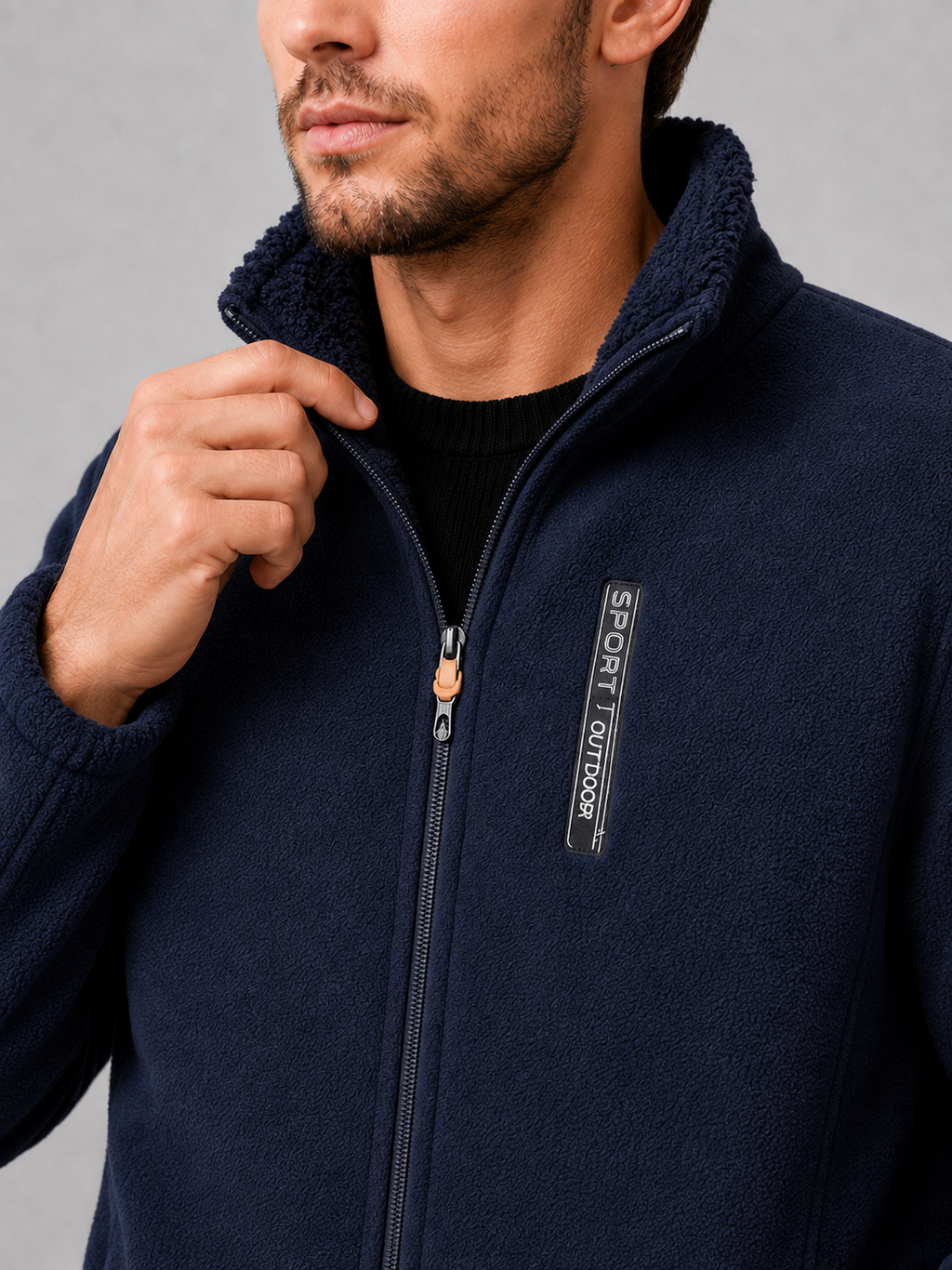 Close-up of a navy polar fleece jacket showing the soft fleece texture, windproof construction, full zipper, stand collar, pockets, cuffs, and stitching details