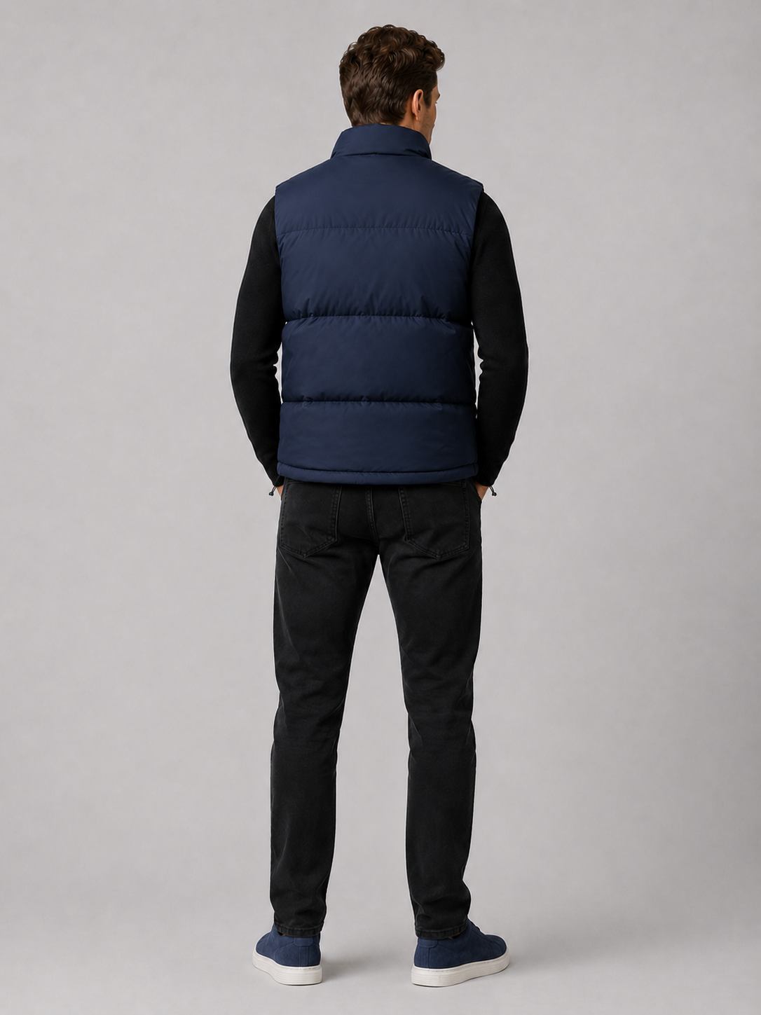 Back view of a man wearing a navy puffer vest showing the quilted construction, stand collar, and comfortable fit