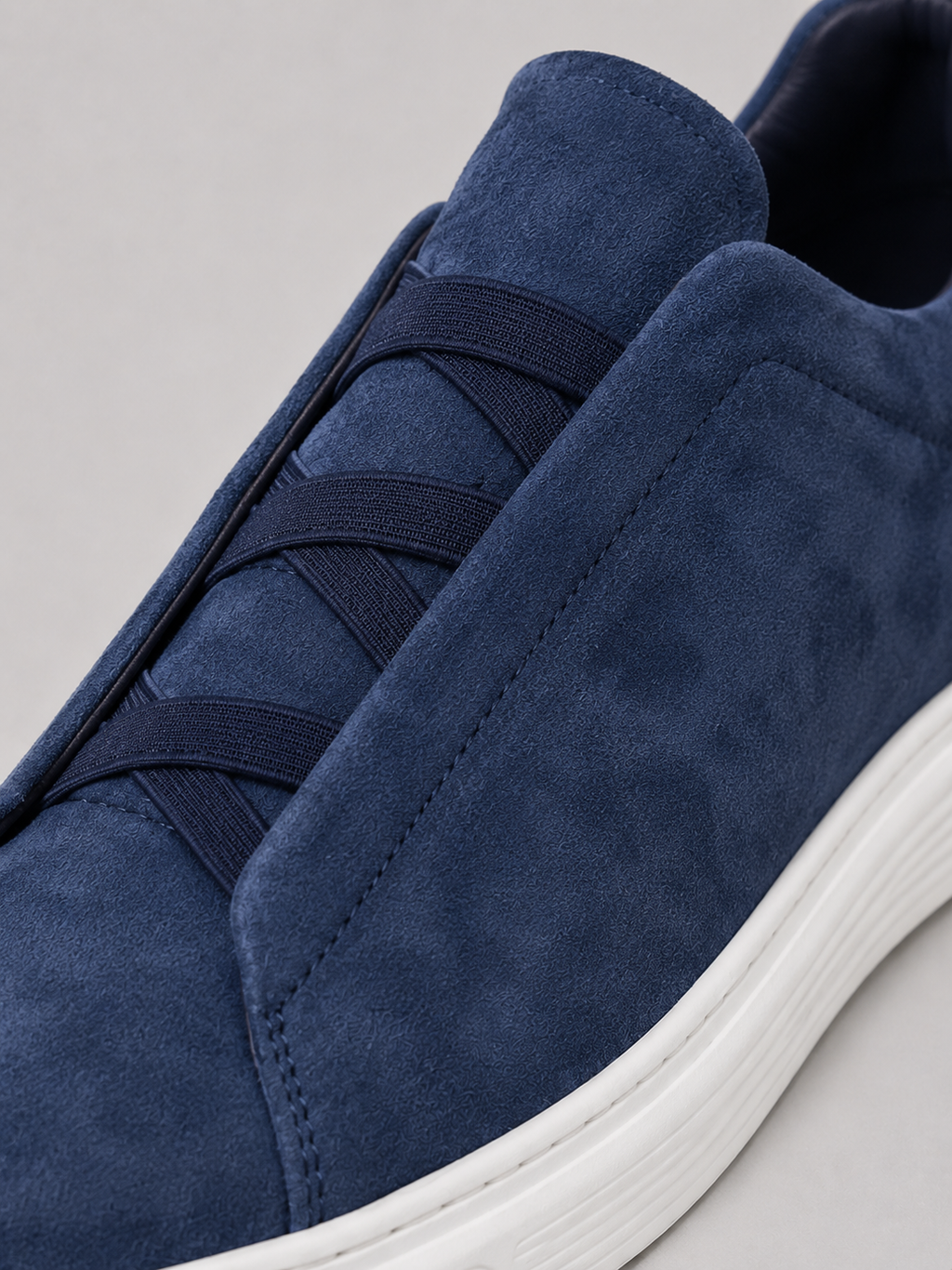 Close up of navy suede slip on sneakers showing soft suede texture and clean stitching detail