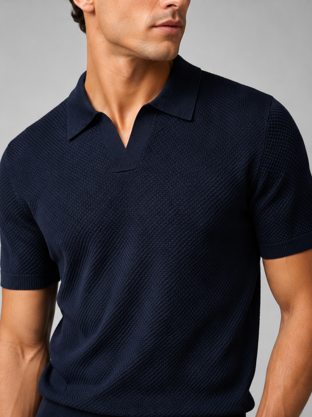 Close up of navy knit polo showing soft breathable stretch fabric and refined collar detail