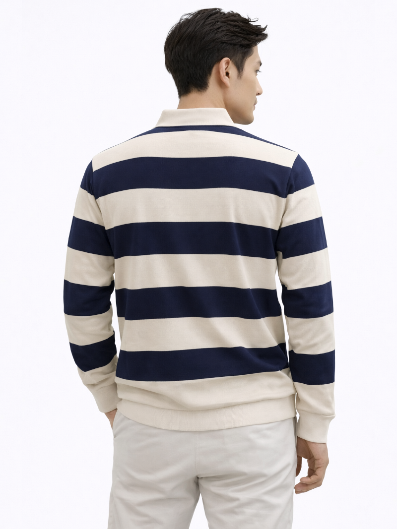 Man wearing a navy and white striped long-sleeve rugby polo and white trousers on a white background