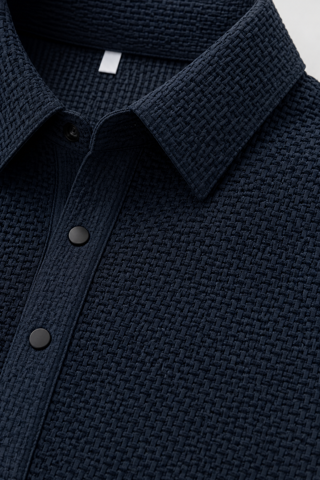 Close up of navy textured knit polo fabric showing breathable weave and button placket detail
