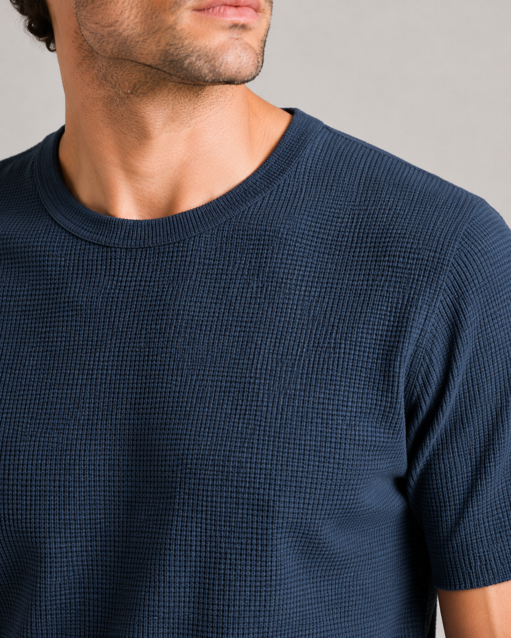 Close up of navy waffle knit fabric showing soft breathable textured weave and lightweight finish