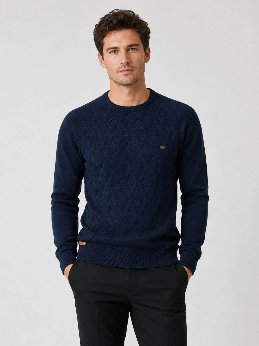 Front view of a man wearing a navy argyle crew neck sweater with long sleeves and a warm knit pattern