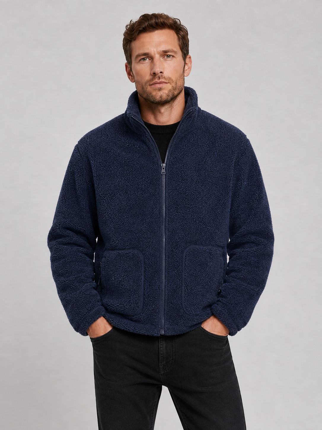 Front view of a man wearing a navy full zip fleece jacket with a stand collar, loose fit, long sleeves, and warm fall winter design