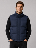 Front view of a man wearing a navy puffer vest with a thick insulated design, stand collar, and full zip front