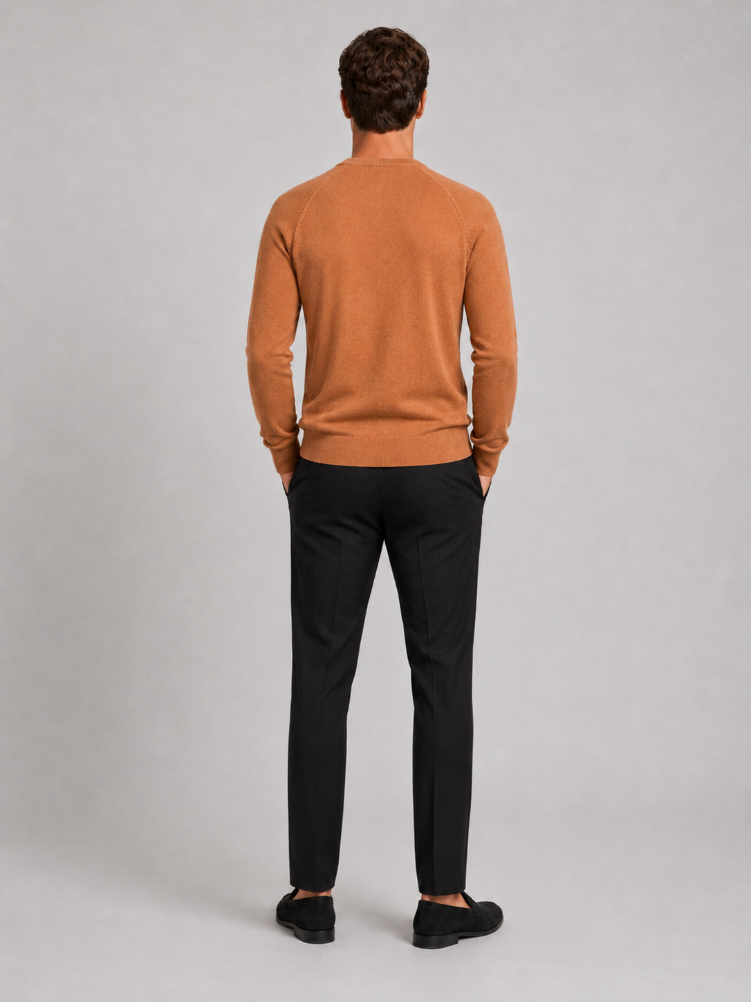 Back view of a man wearing an orange argyle sweater showing the crew neck, long sleeves, and comfortable fit