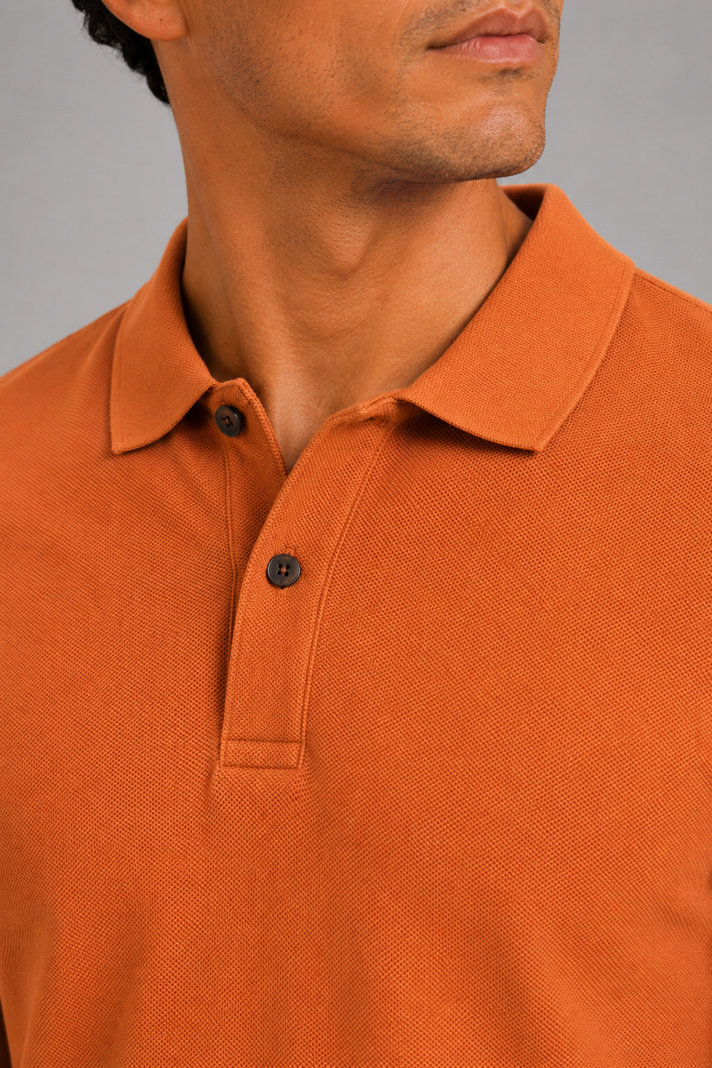 Close up of orange polo shirt showing smooth silk touch fabric and refined collar detail