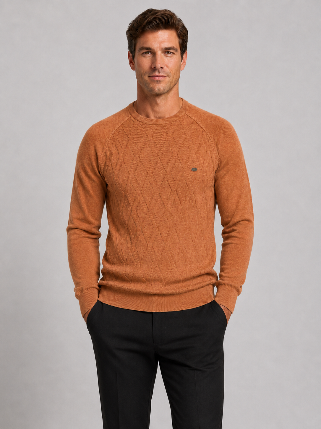 Front view of a man wearing an orange argyle crew neck sweater with long sleeves and a warm knit pattern