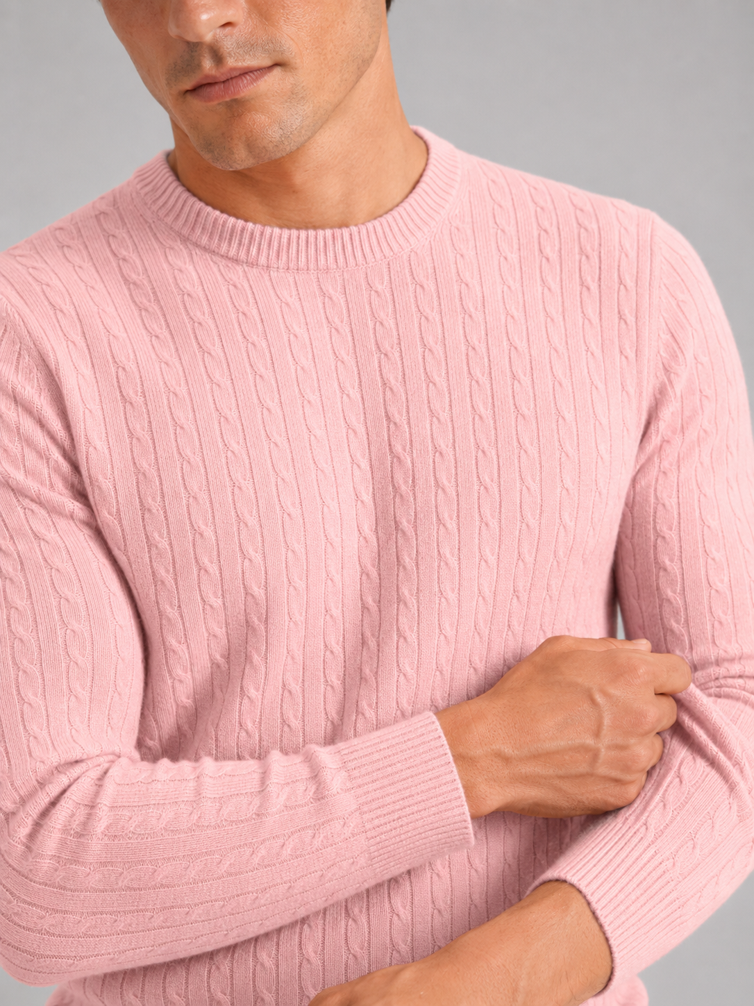 Close up of pink cable knit sweater showing soft textured fabric and clean crew neck detail
