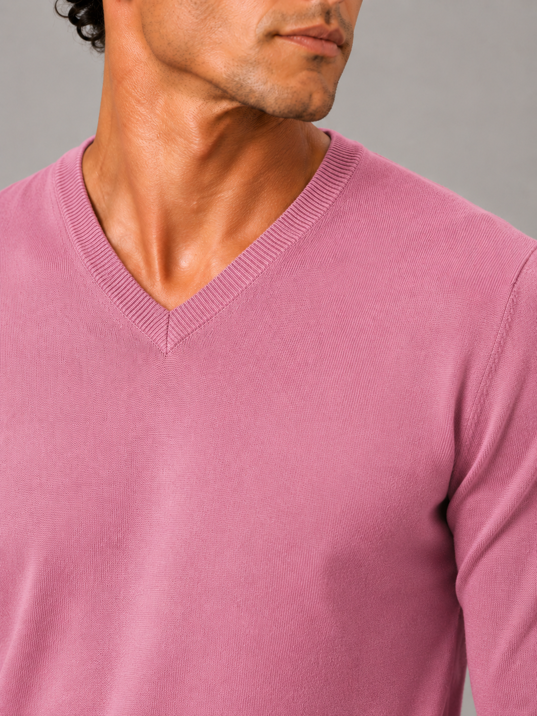 Close up of pink knit sweater showing soft lightweight fabric and refined v neck detail