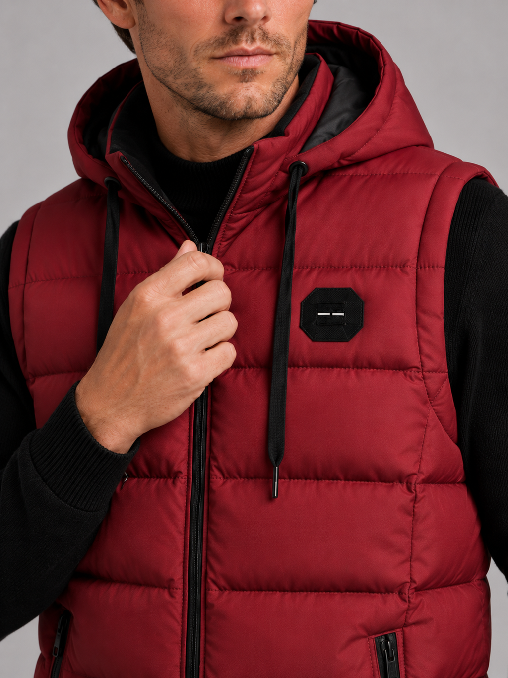 Close-up of a red hooded puffer vest showing the cotton padding, thick insulation, zipper closure, hood, pockets, armholes, and stitching details
