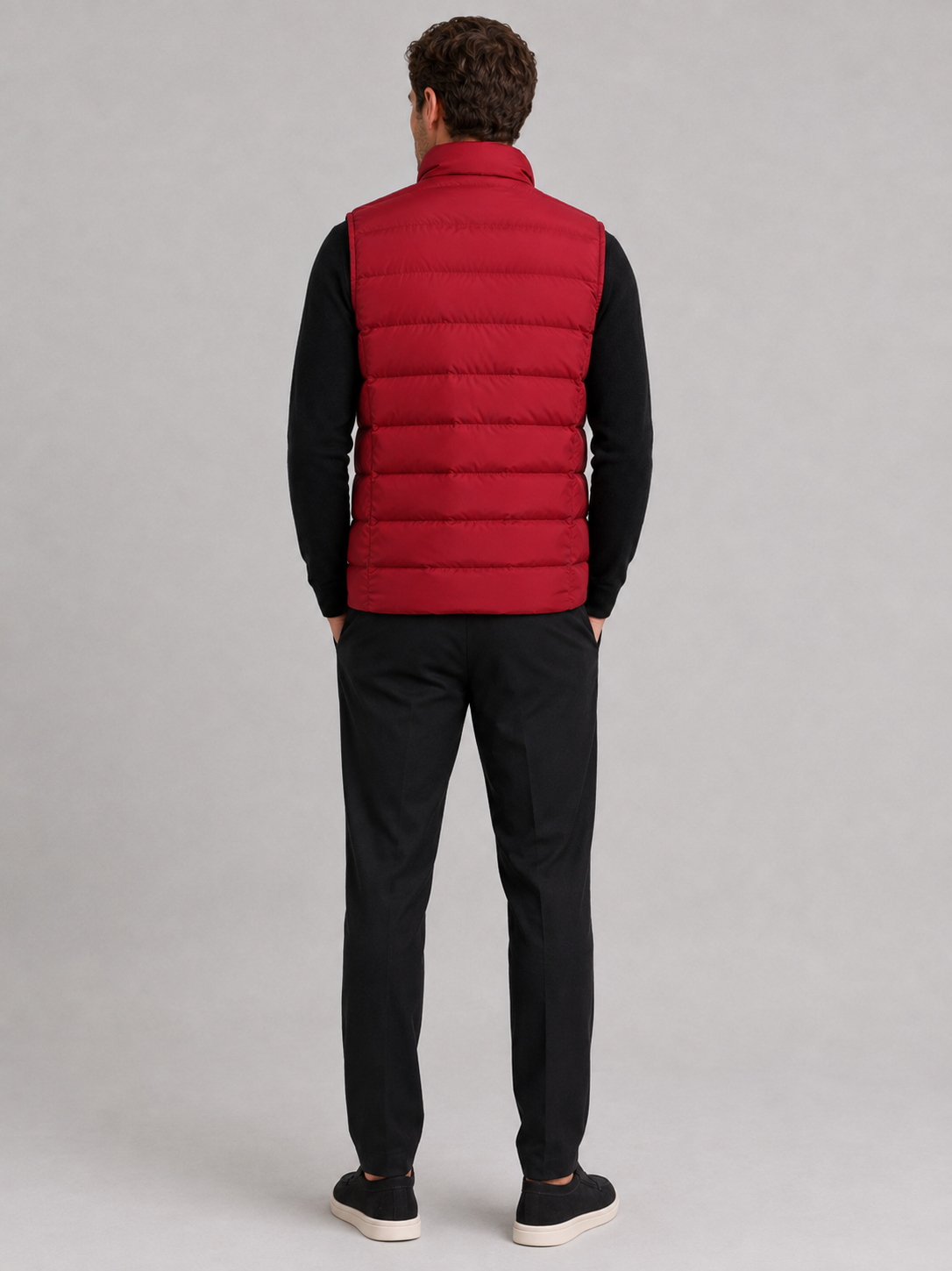 Back view of a man wearing a red puffer vest showing the padded construction, sleeveless cut, and comfortable fit
