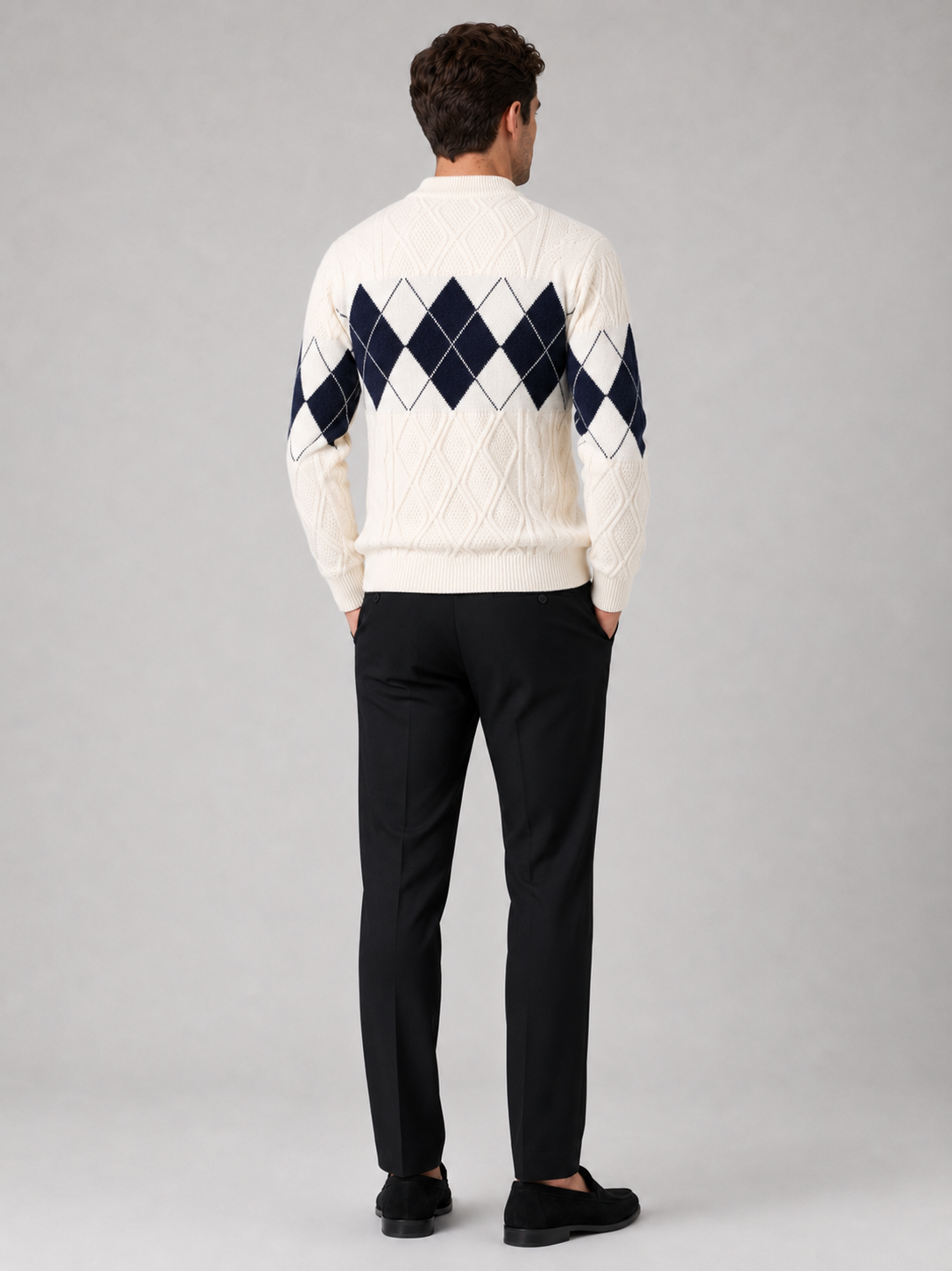 Back view of a man wearing a white argyle cable knit sweater showing the mock neck, long sleeves, thick knit fabric, and comfortable fit