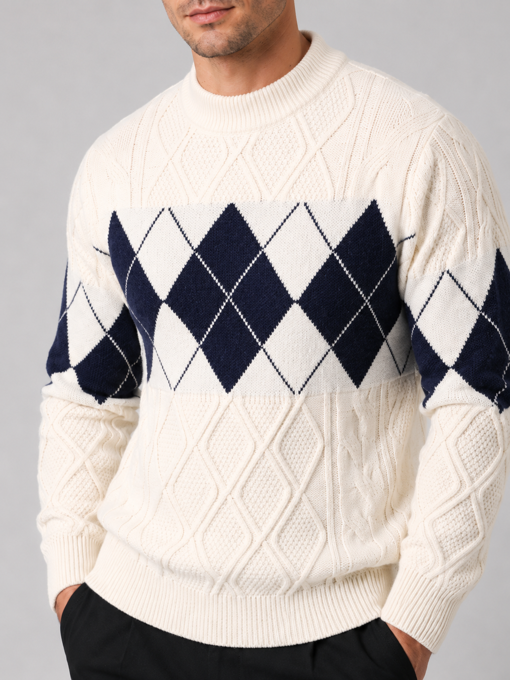 Close-up of a white argyle cable knit sweater showing the cable knit texture, argyle pattern, patchwork details, mock neck, ribbed cuffs, and hem