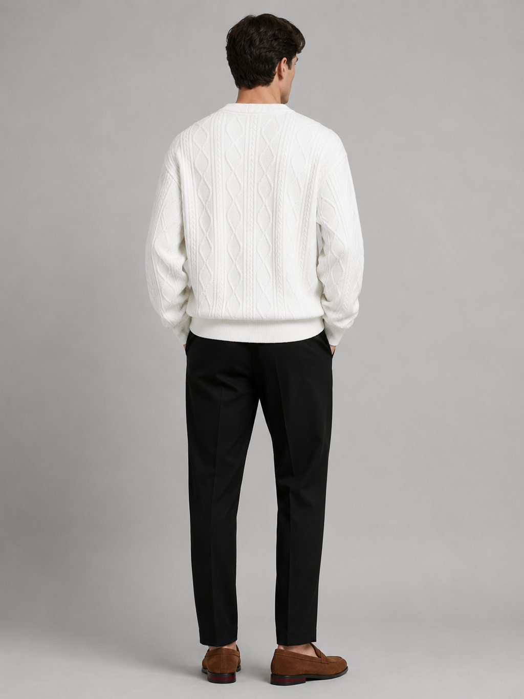 Back view of a man wearing a white cable knit cardigan sweater showing the relaxed oversized fit, long sleeves, and warm knit construction