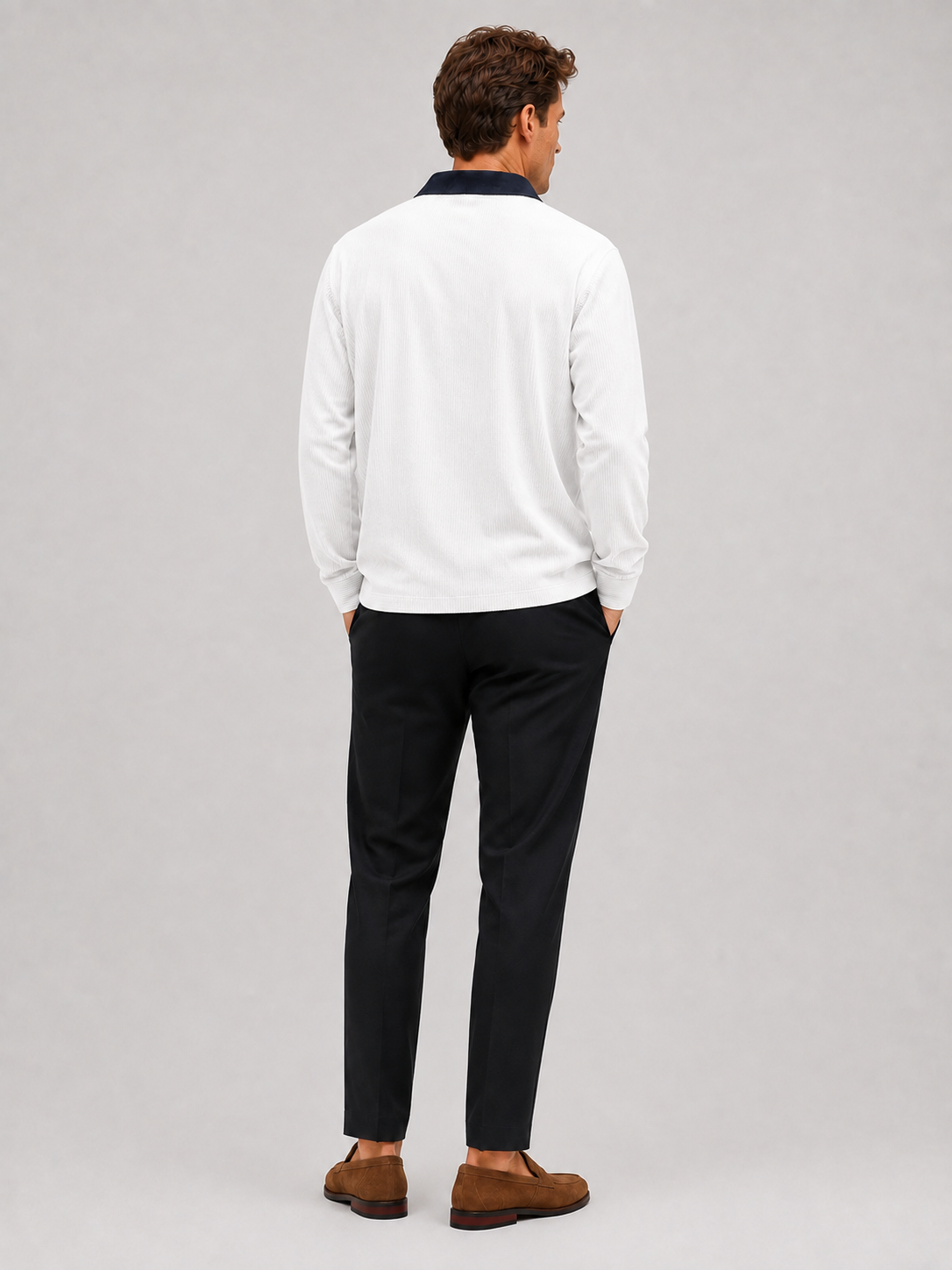 Back view of a man wearing a white corduroy polo shirt showing the long sleeves, relaxed fit, and soft textured fabric