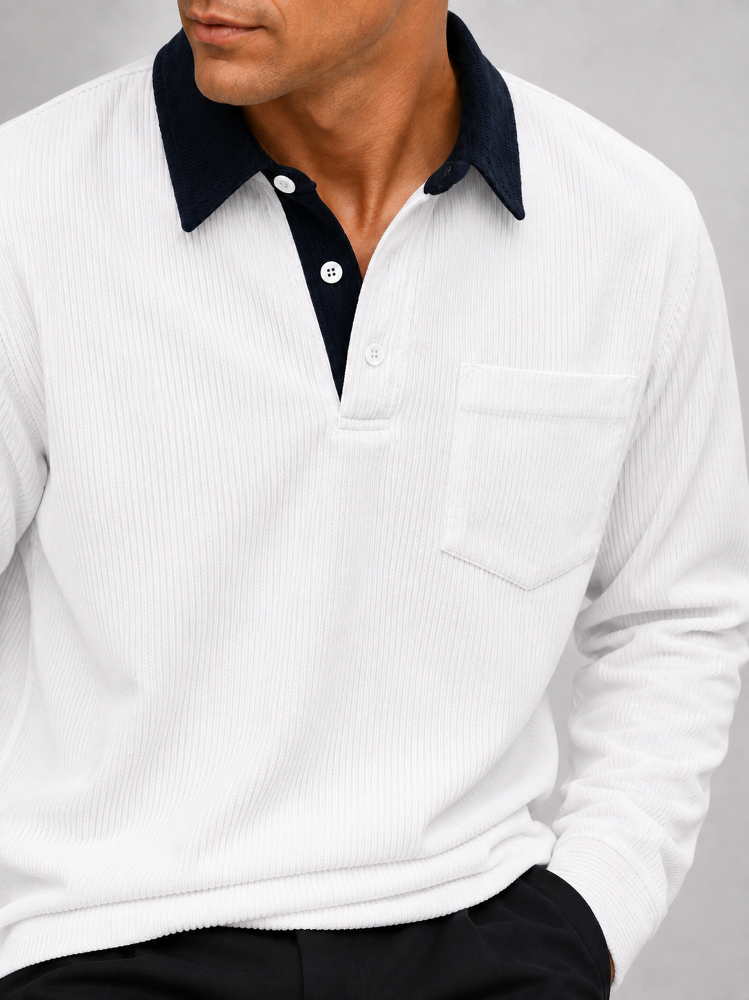 Close-up of a white corduroy polo shirt showing the textured polyester fabric, contrast turn-down collar, button placket, cuffs, and stitching