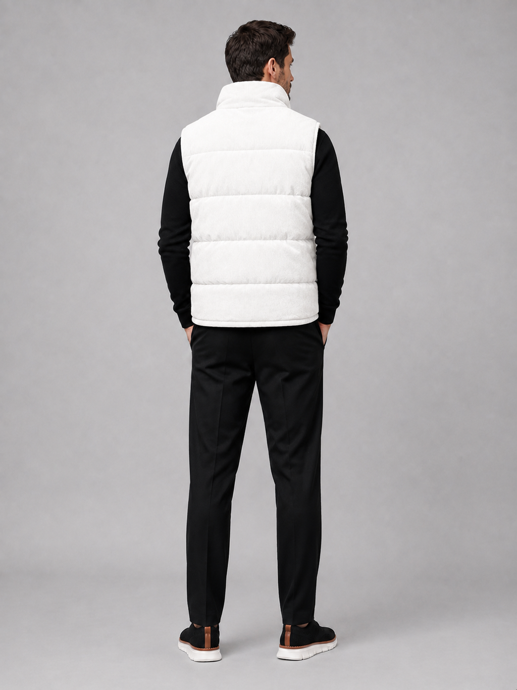 Back view of a man wearing a white corduroy puffer vest showing the sleeveless cut, padded construction, and comfortable fit