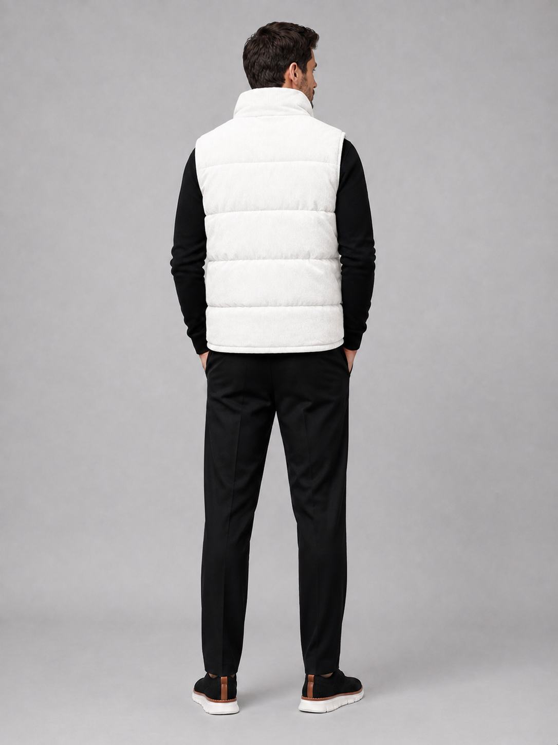 Back view of a man wearing a white corduroy puffer vest showing the sleeveless cut, padded construction, and comfortable fit