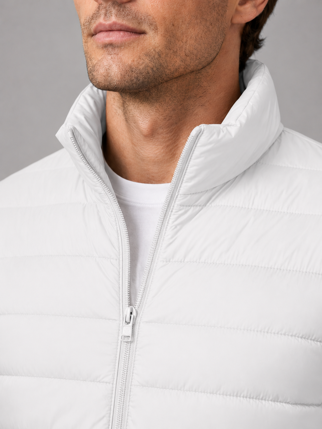 Close up of white down puffer jacket showing insulated quilting, stand collar, and weather resistant fabric detail