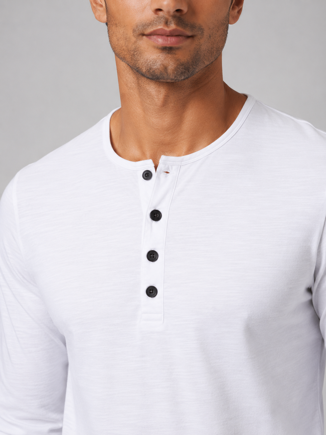 Close up of white henley shirt fabric showing soft smooth breathable texture and button detail